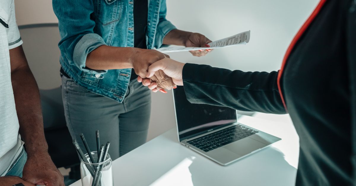 Two people shaking hands over a desk signifies a business agreement or partnership.