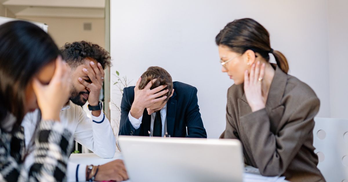 A group of stressed business professionals in an office setting, overwhelmed by work.