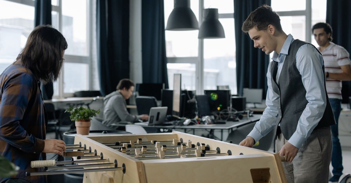 Office workers taking a break to play foosball in a modern startup environment.