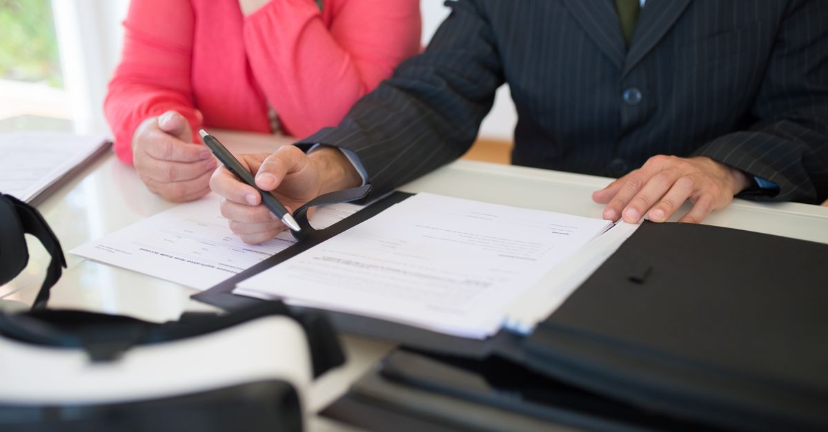 Close-up of professionals signing a business contract indoors, emphasizing agreement and documentation.