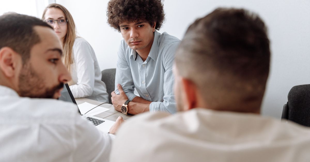A diverse group of business professionals engaged in a meeting within a modern office setting.