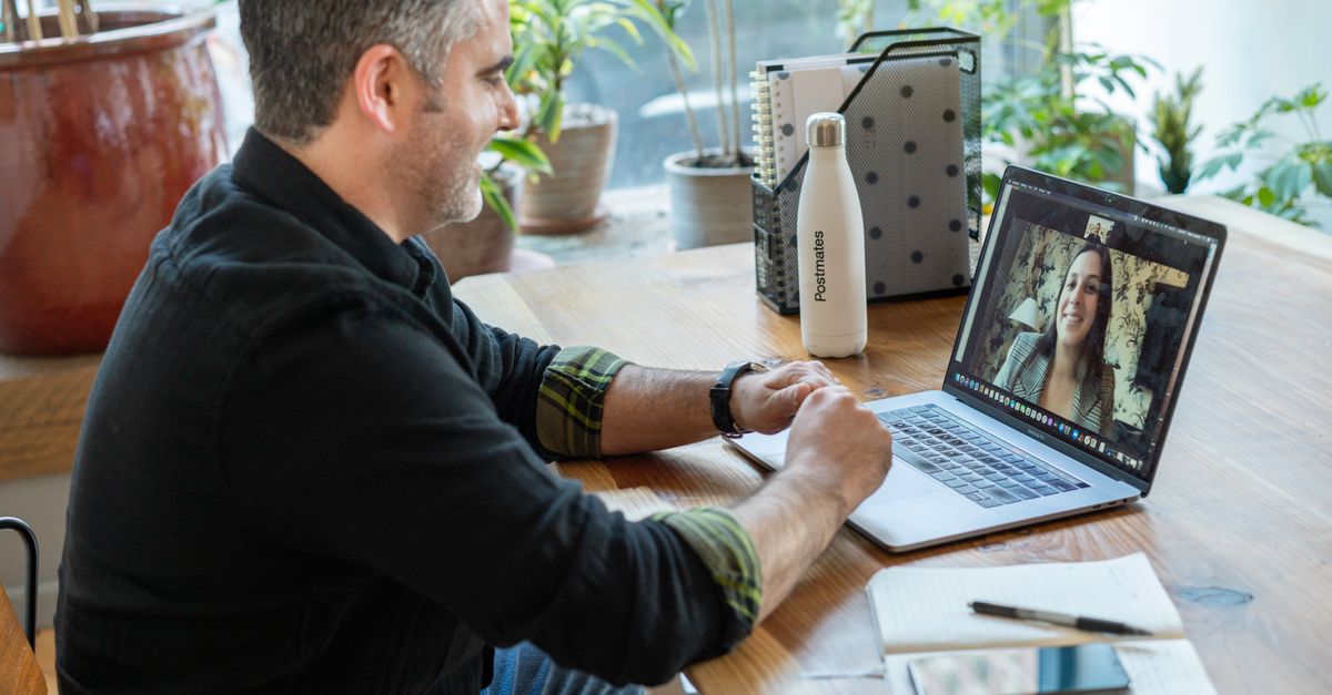 A man participates in a virtual meeting from his home workspace, focusing on remote work.