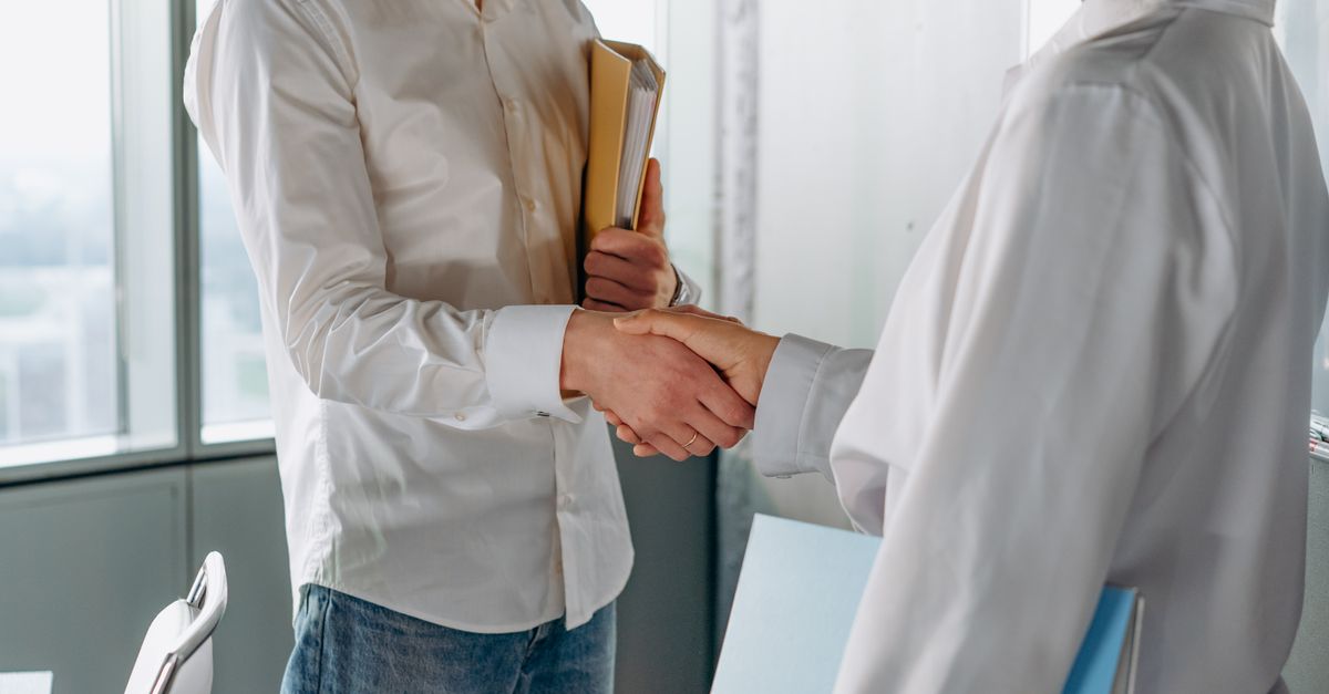Two professionals shake hands indoors, symbolizing agreement or partnership in business.